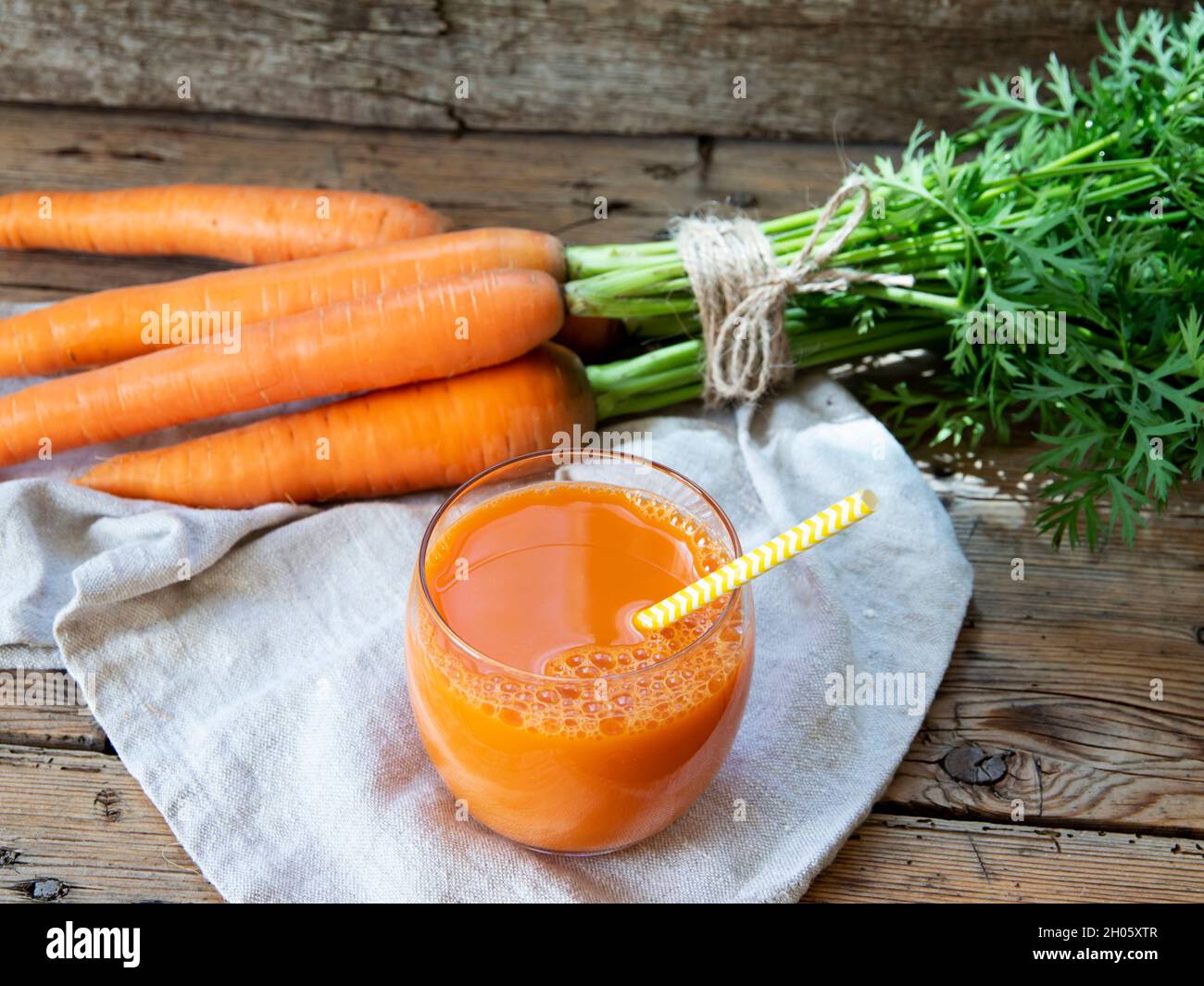 Fresh squeezed carrot juice in a glass on a wooden surface, rustic style  Healthy eating, detox, dieting and vegetarian concept. Stock Photo