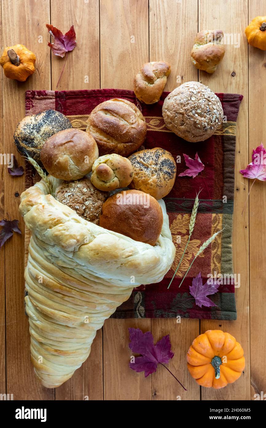 Bread cornucopia with buns spilling out and Thanksgiving decorations all around. Stock Photo