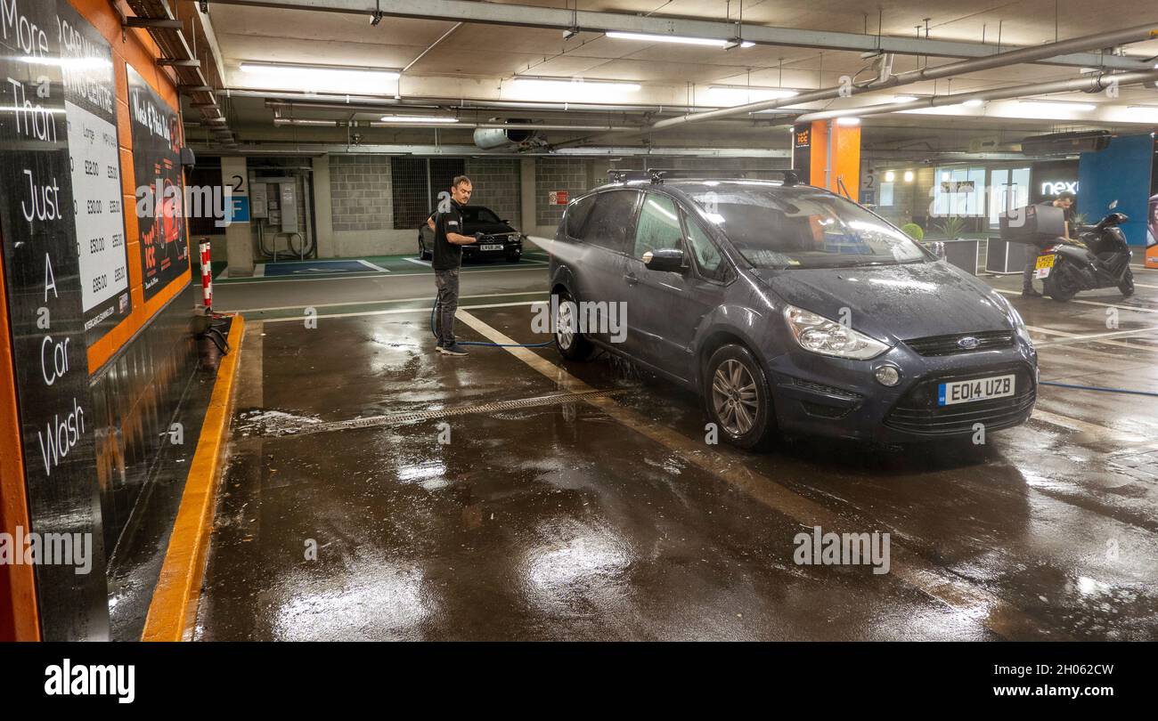 Newbury, Berkshire, England, UK. 2021. Car wash worker cleaning a car
