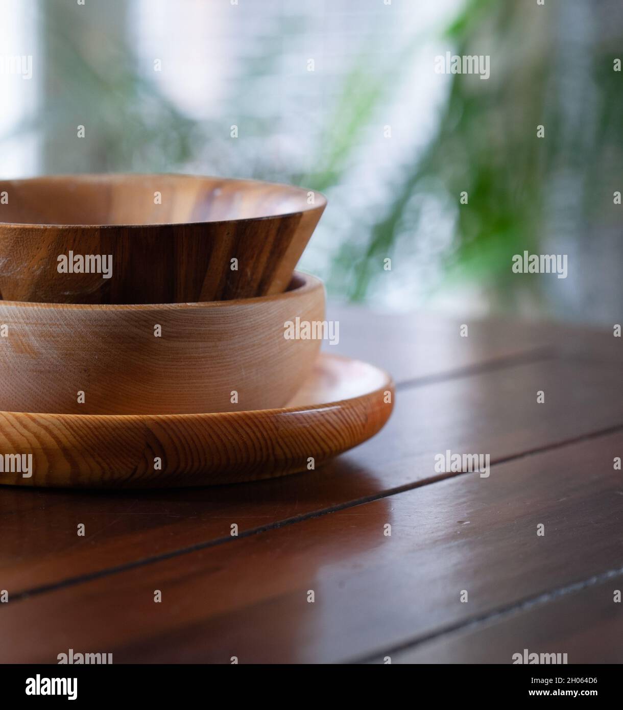 Three different kinds of wooden bowls stacked on wooden table. Stock Photo