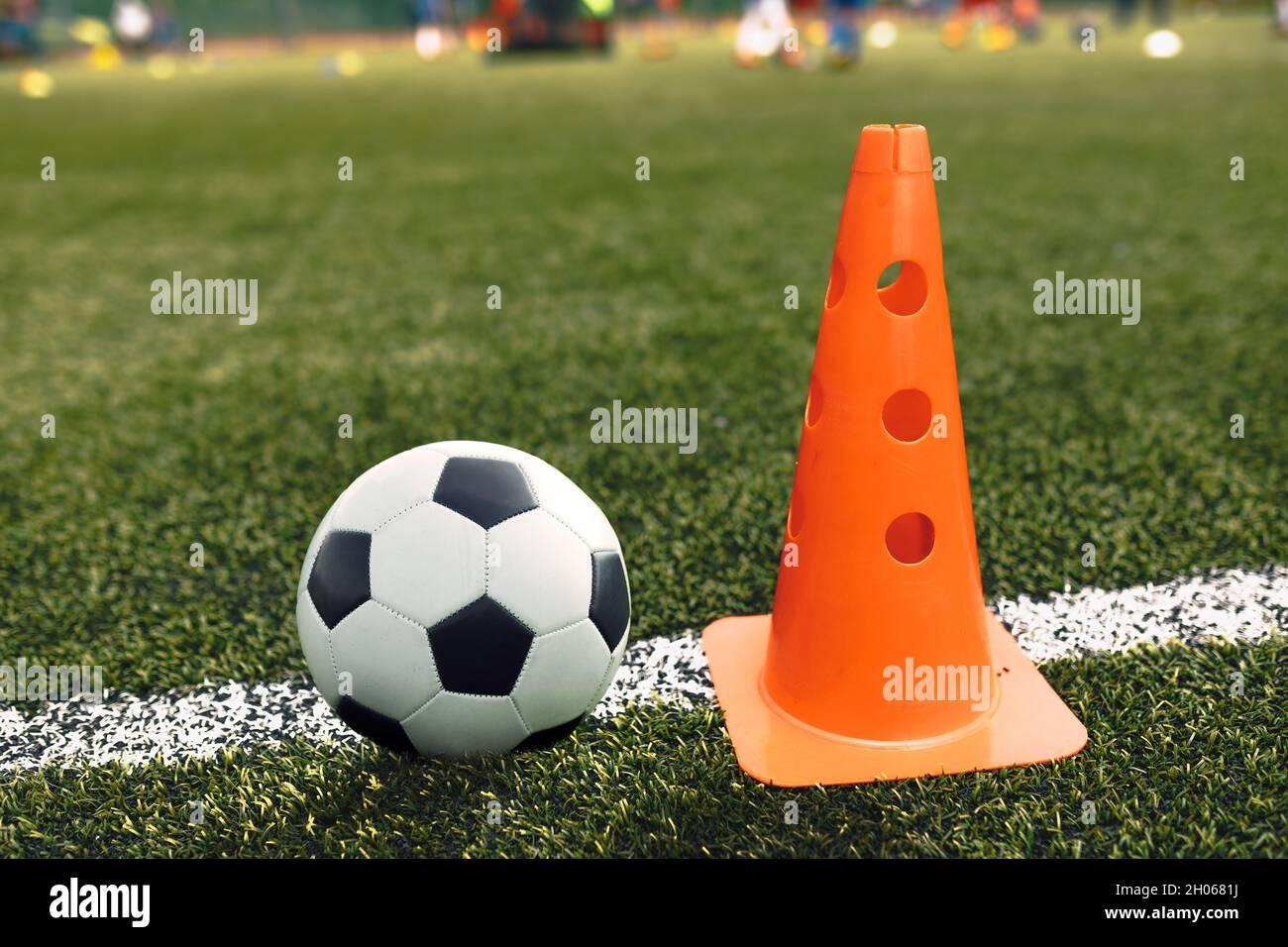 Soccer Ball and Training Cone Lying on Football Pitch Sideline. Soccer Training Equipment on School Practice Pitch Stock Photo