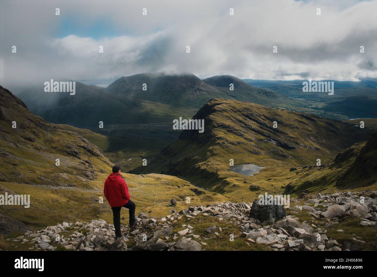 A hiker at the top of the mountain views the magnificent landscape of the Isle of Skye. Bla Bheinn, Isle of Skye, Scotland  Stock Photo