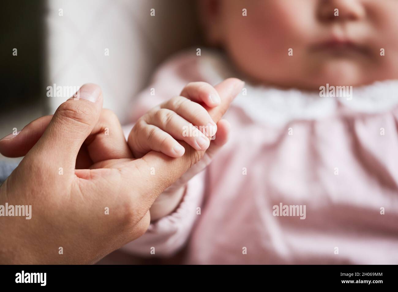 Close-up of newborn baby holding hand of her mother Stock Photo