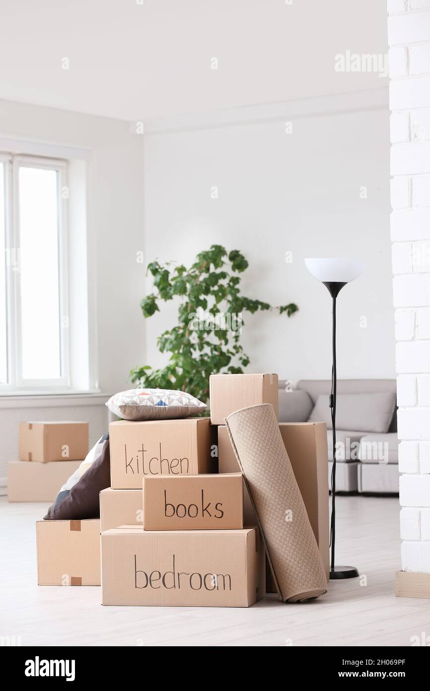 Pile of moving boxes and household stuff in living room Stock Photo - Alamy