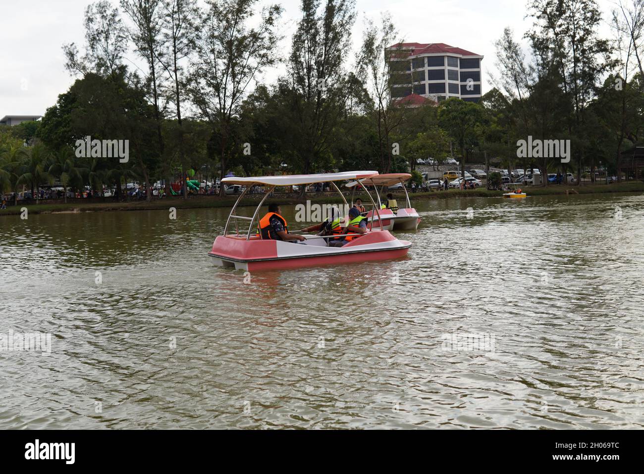 Public park visitors enjoy paddling boats and nature green lake scenery with family members at Kuantan Malaysia Stock Photo
