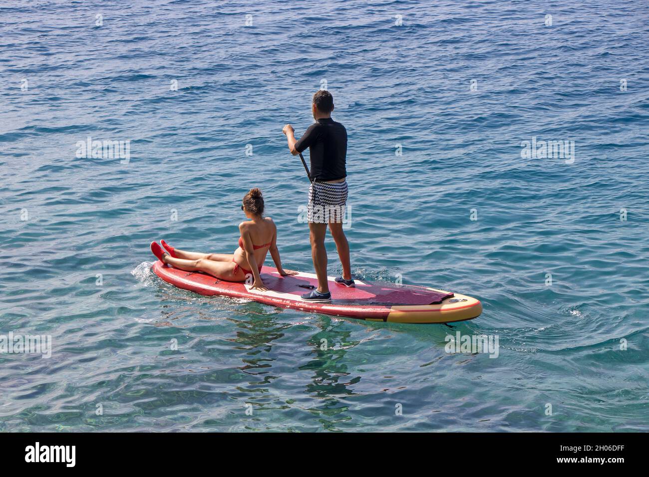 Young couple on stand up paddleboard surfboard surfing together on summer vacation Stock Photo