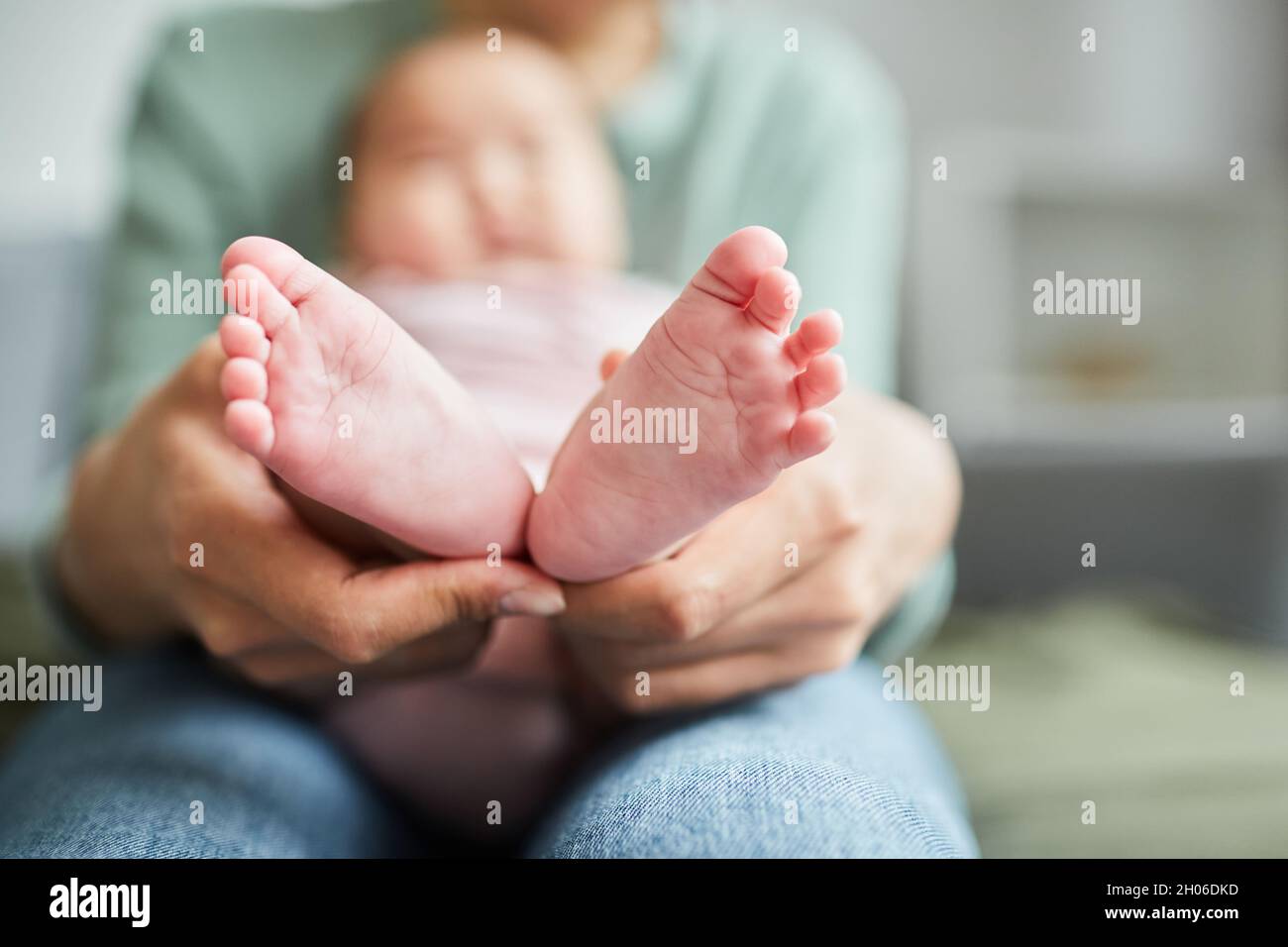 Close-up of young mother holding the little feet of her baby while she lying on her knees Stock Photo