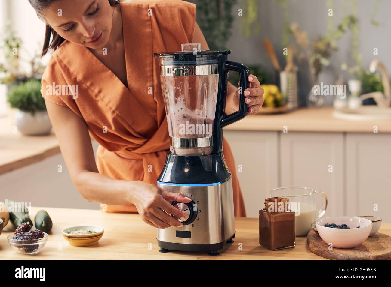 https://c8.alamy.com/comp/2H06FJ8/young-female-mixing-ingredients-in-electric-blender-while-making-smoothie-in-the-kitchen-2H06FJ8.jpg