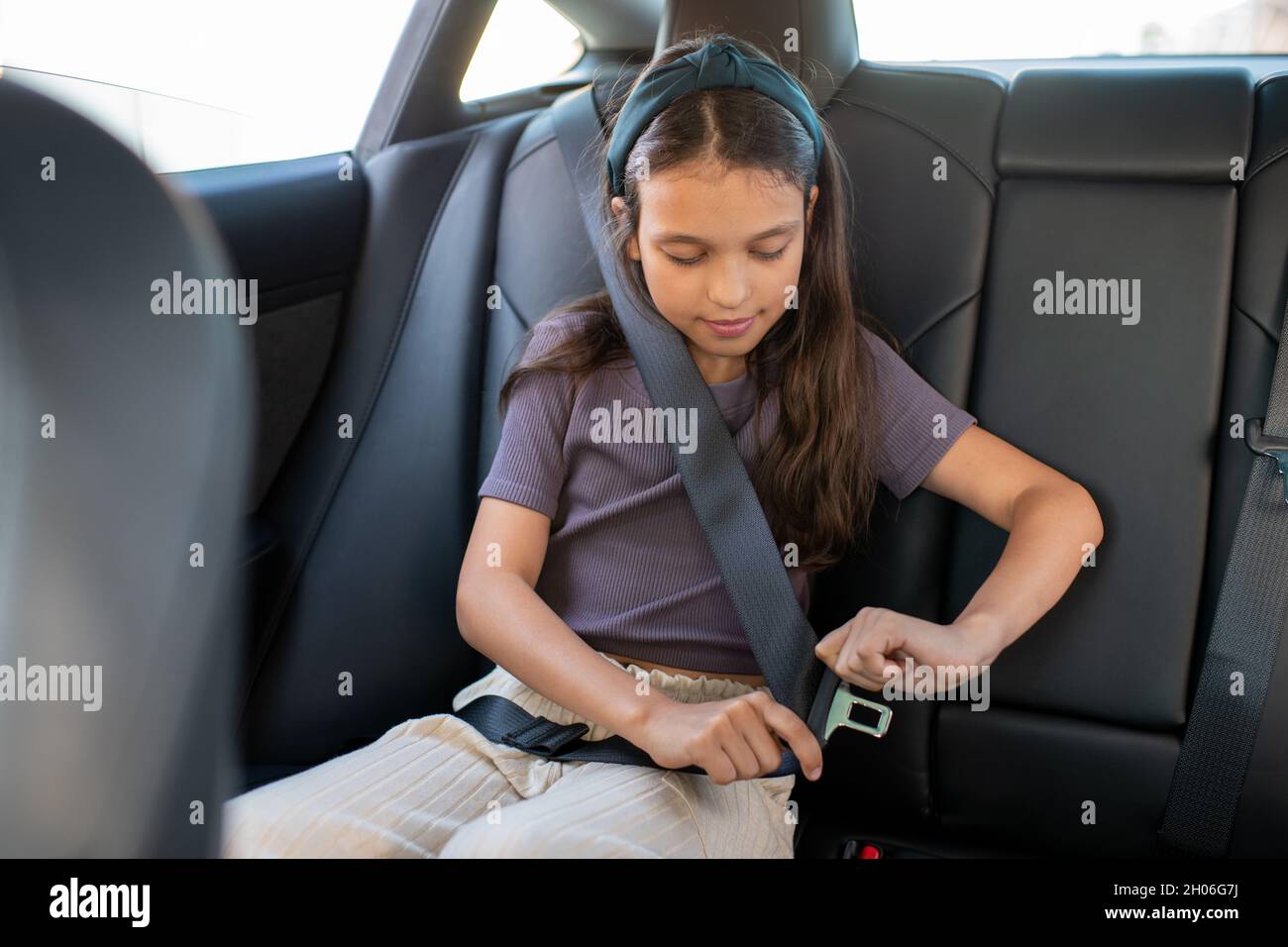 https://c8.alamy.com/comp/2H06G7J/adorable-schoolgirl-fastening-seatbelt-while-sitting-inside-electric-car-2H06G7J.jpg