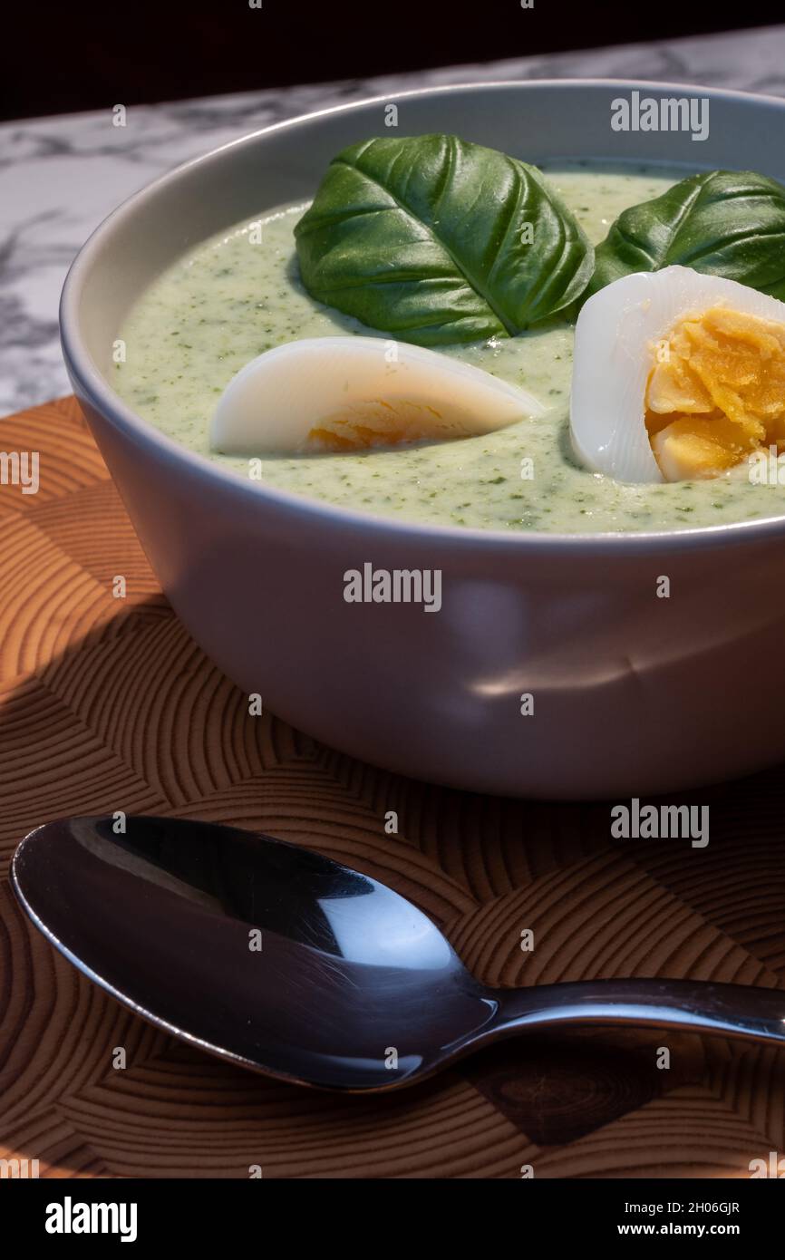 Helsinki / Finland - OCTOBER 10, 2021: Traditional Finnish cuisines; closeup of a plate of spinach soup with boiled egg and basil topping Stock Photo