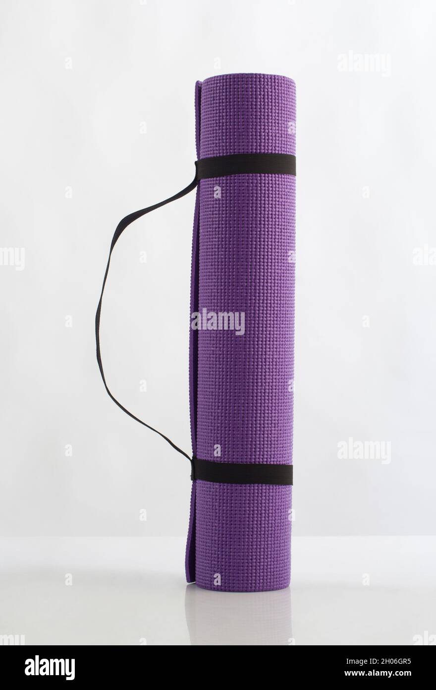Rolled up purple yoga mat isolated on white background Stock Photo