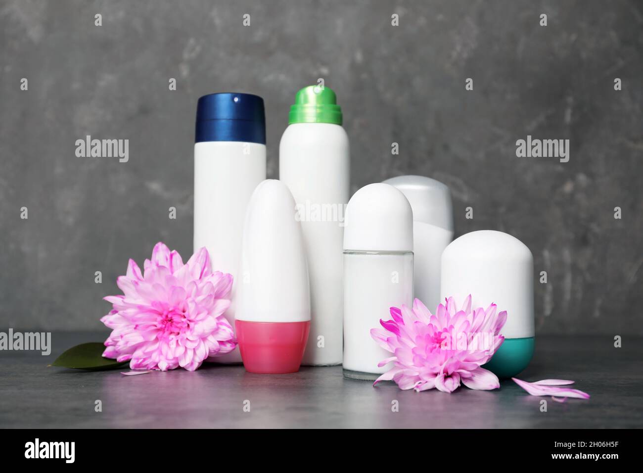 Different deodorants and flowers on table. Personal hygiene Stock Photo