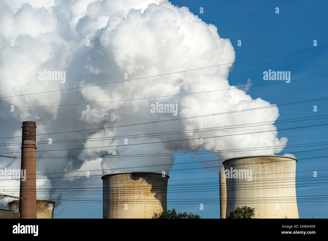 White clouds of water vapor emerging from the cooling tower of a power
