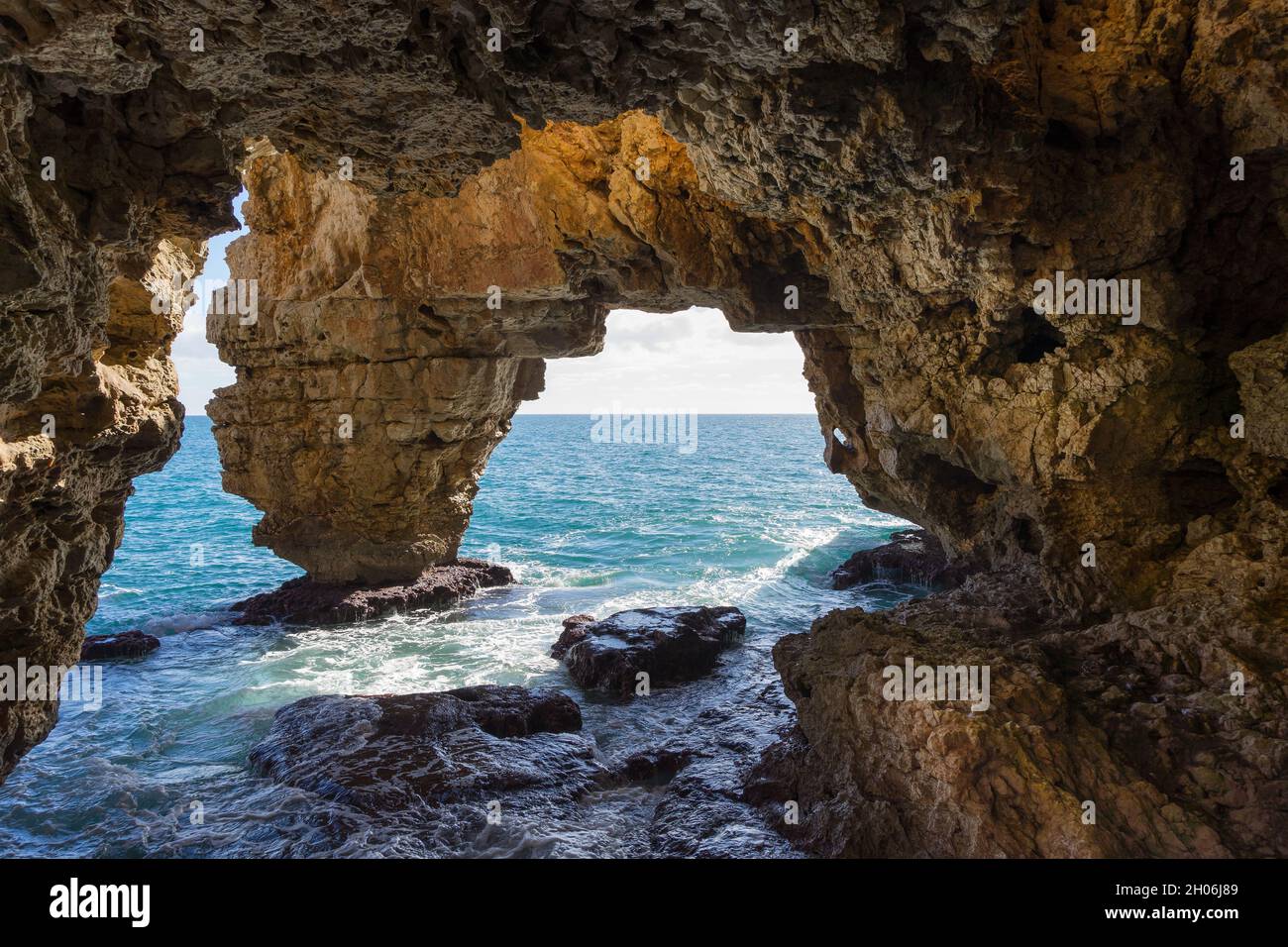 Limestone cliffs on the Mediterranean coast Cova del Archs rock cave and clear blue water travel destination Costa Blanca Spain Stock Photo