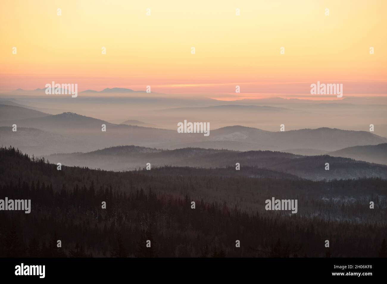 Majestic scenery of pink and yellow sky and mountains covered with forest at dawn Stock Photo