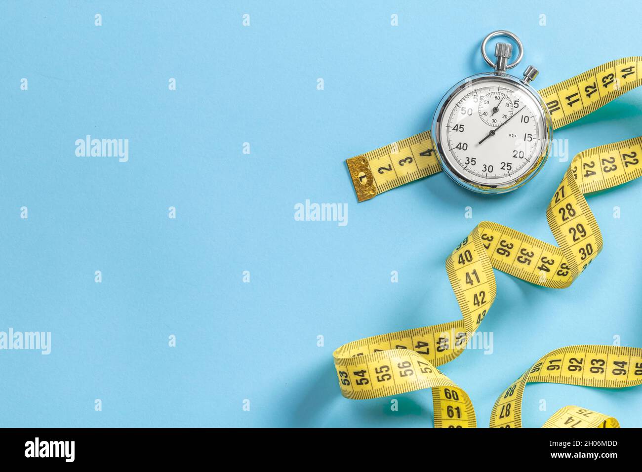 Fast workouts. Yellow measuring tape meter and stopwatch on a blue background. Template Copy space for text. Stock Photo