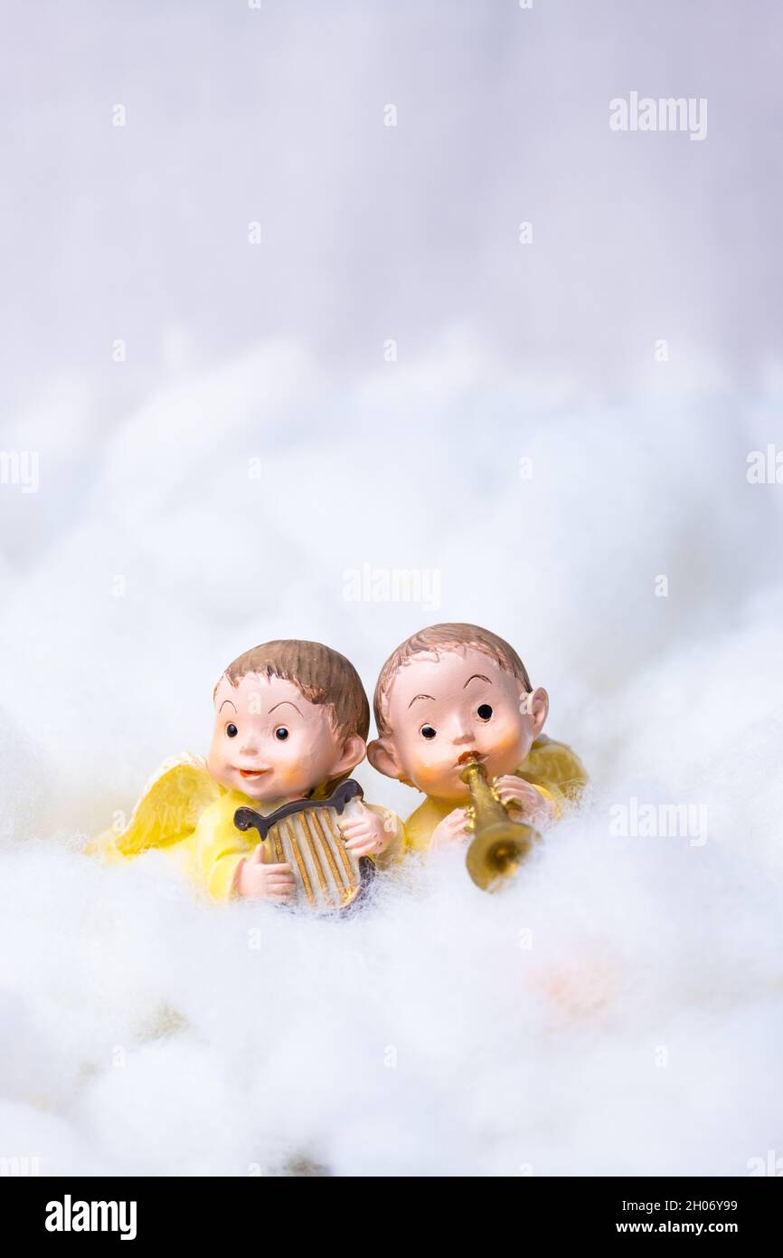 Two figures of angels on cotton simulating clouds. Christmas greeting concept. Copy Space Stock Photo