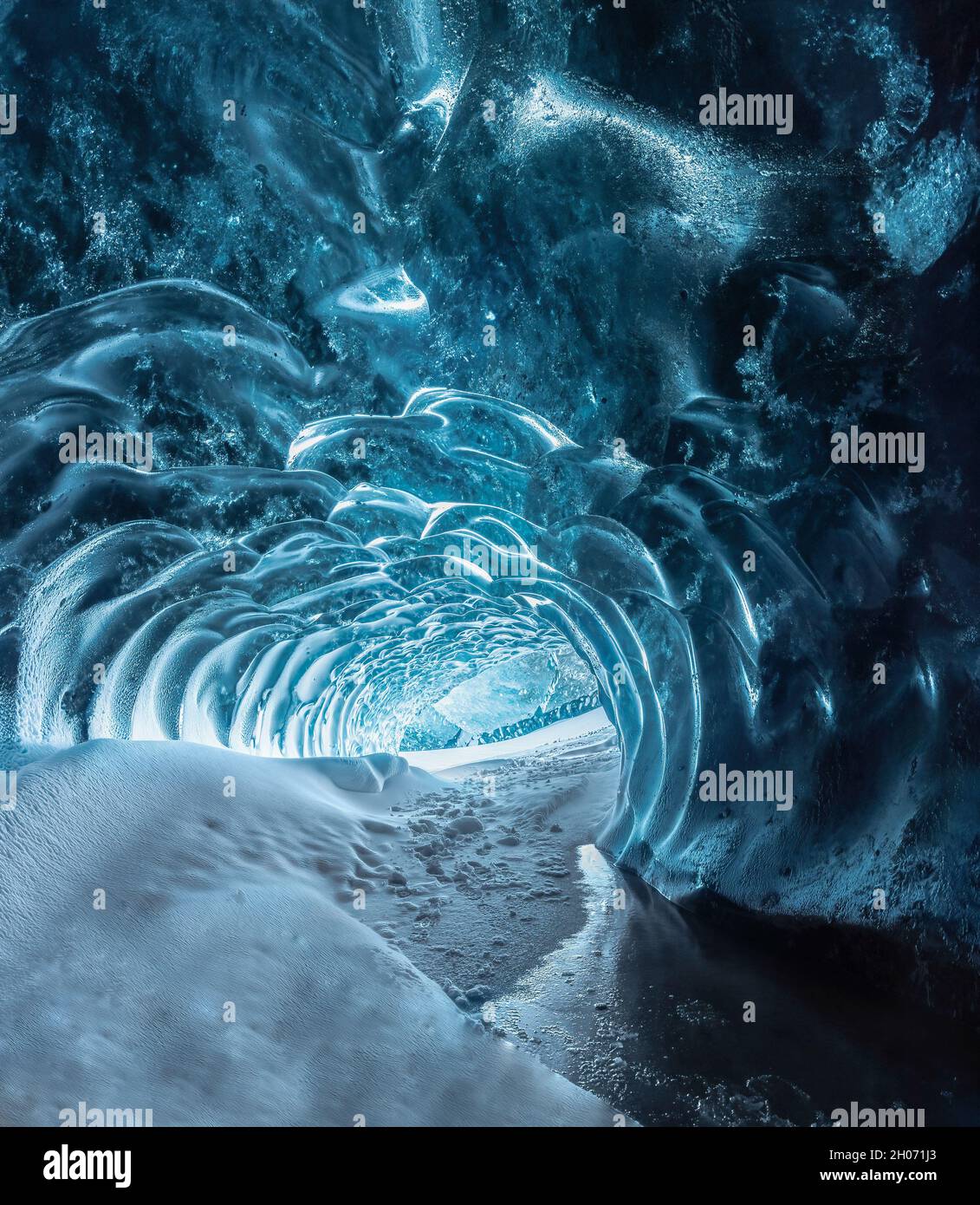 Blue crystal ice cave entrance and an underground river beneath the glacier located in the Highlands in Iceland Stock Photo