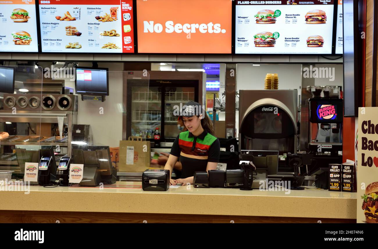Young attractive female staff working behind counter in Burger King fast food outlet, UK Stock Photo