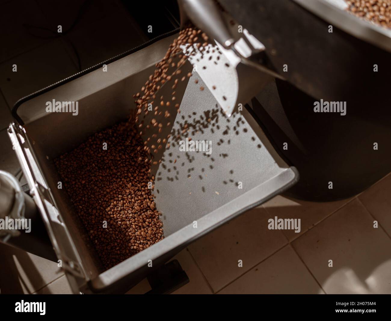 Coffee beans falling from release chute of coffee roaster machine Stock ...