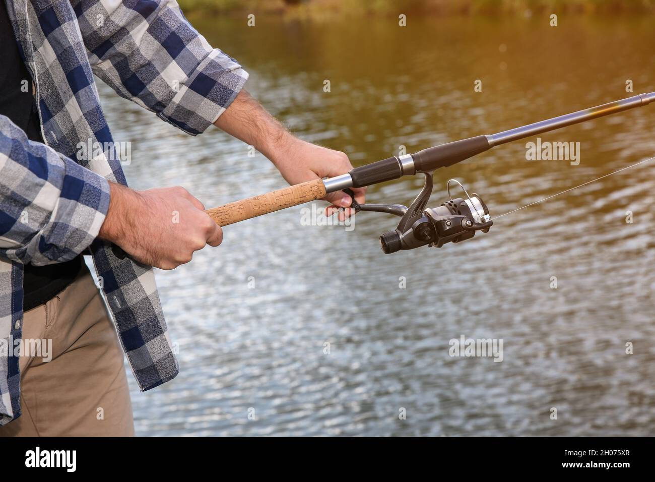 Man with rod fishing at riverside, focus on hands. Recreational