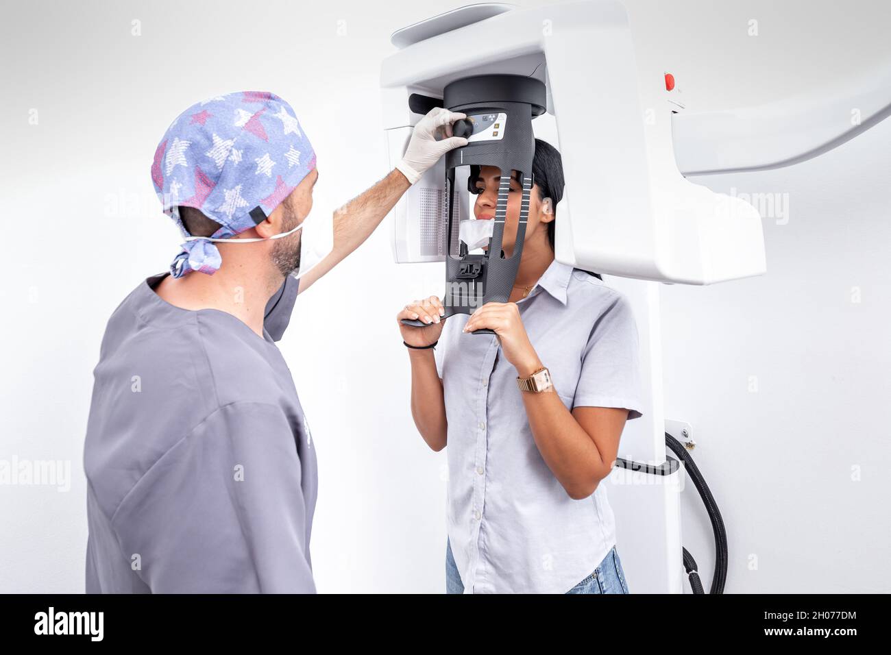 Male dentist graduating a tooth whitening machine used by a female