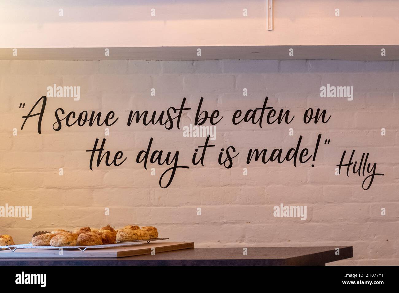 Interior of Hilly's tea shop with her quote, 'A scone must be eaten on the day it is made' painted on the wall, Shere village, Surrey, England, UK Stock Photo