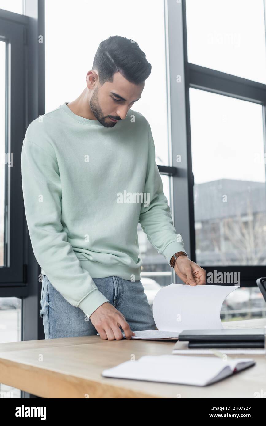 Muslim businessman in casual clothes looking at papers in office Stock Photo