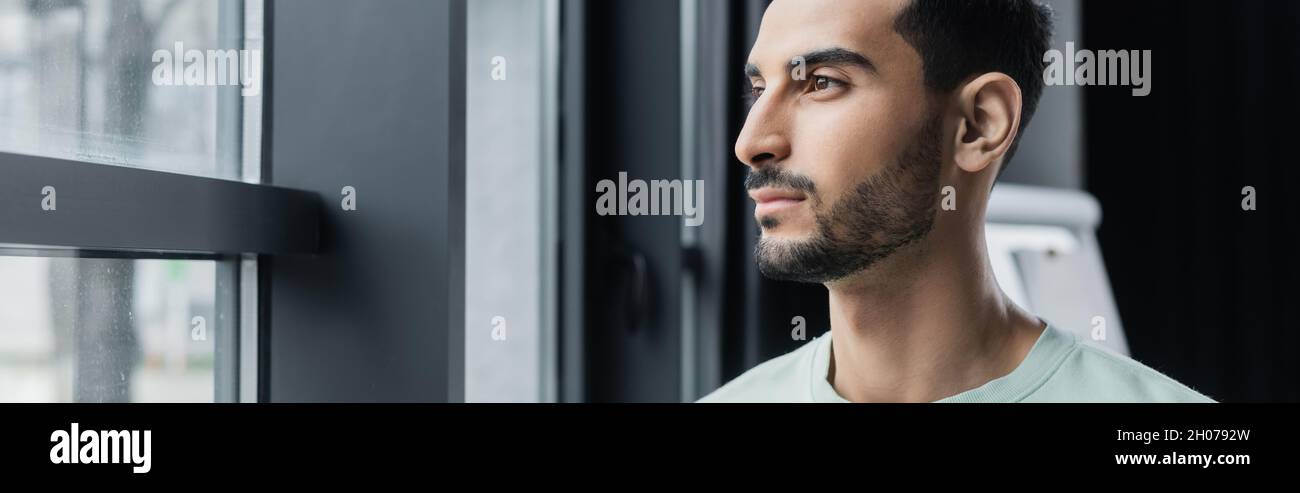 Arabian businessman looking at window in office, banner Stock Photo