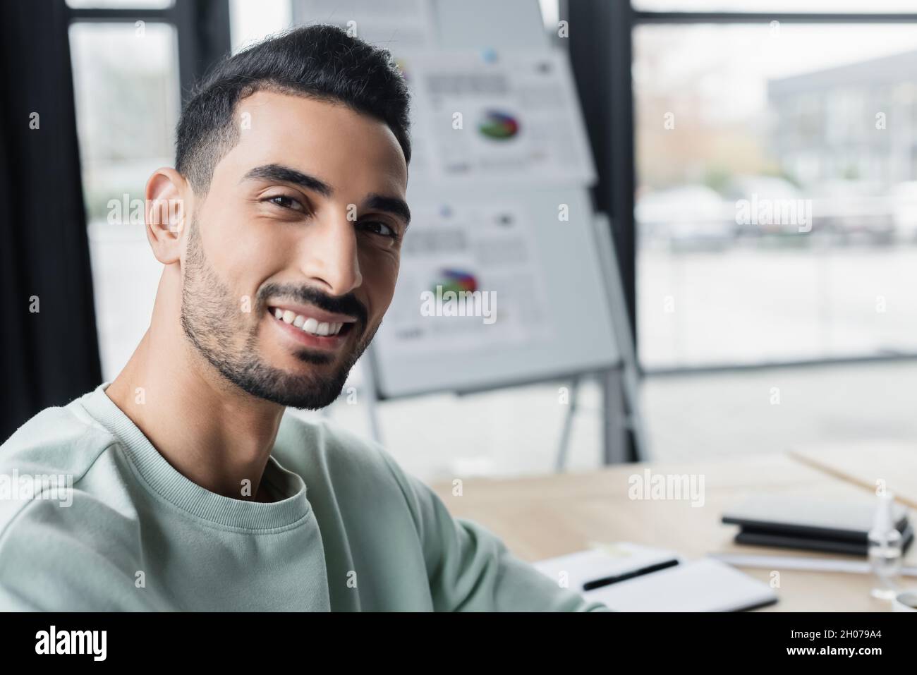Muslim businessman in casual clothes smiling at camera in office Stock Photo