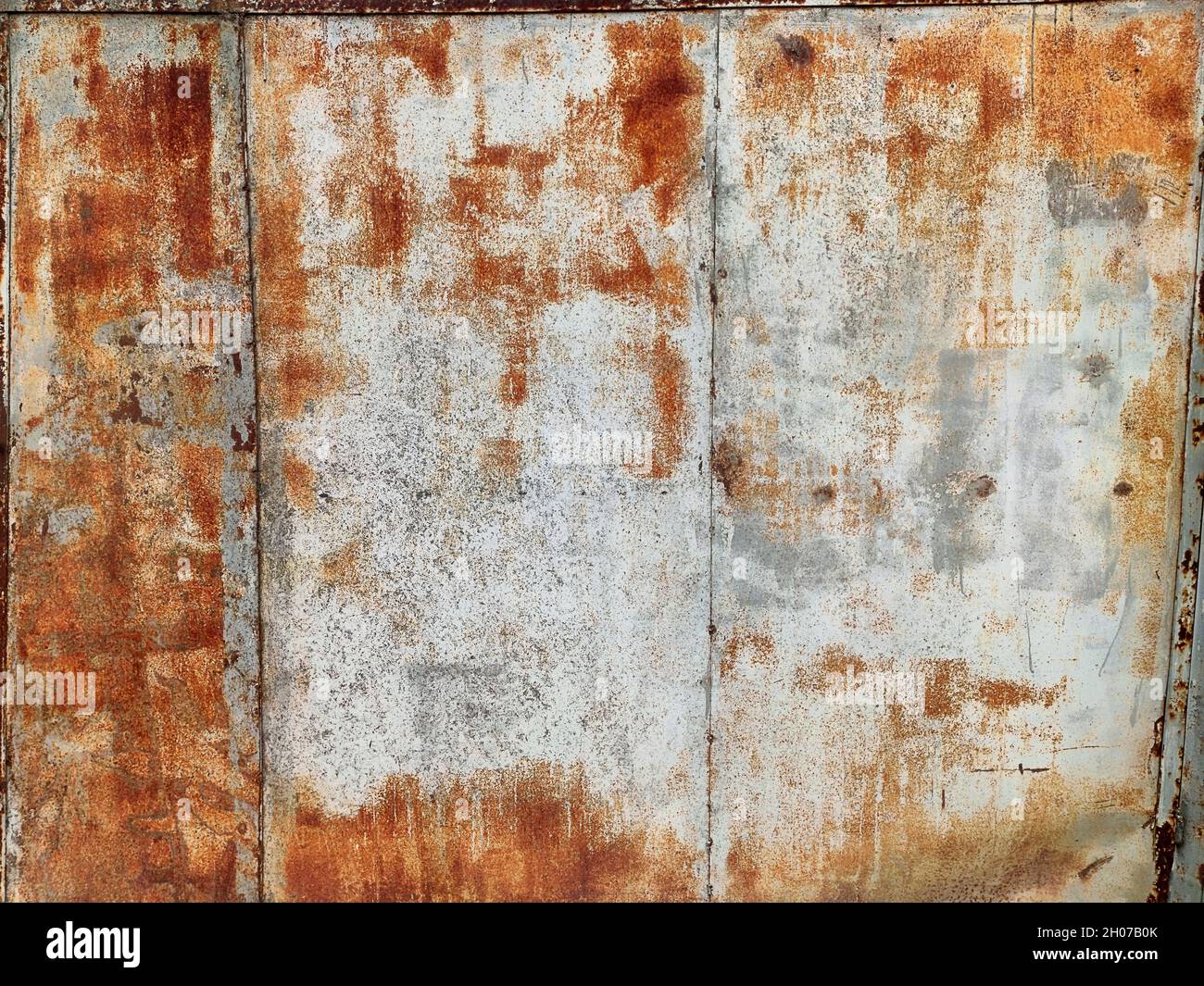 Corroded metal background. Rusted white painted metal wall. Rusty metal background with streaks of rust. Rust stains. The metal surface rusted spots. Stock Photo