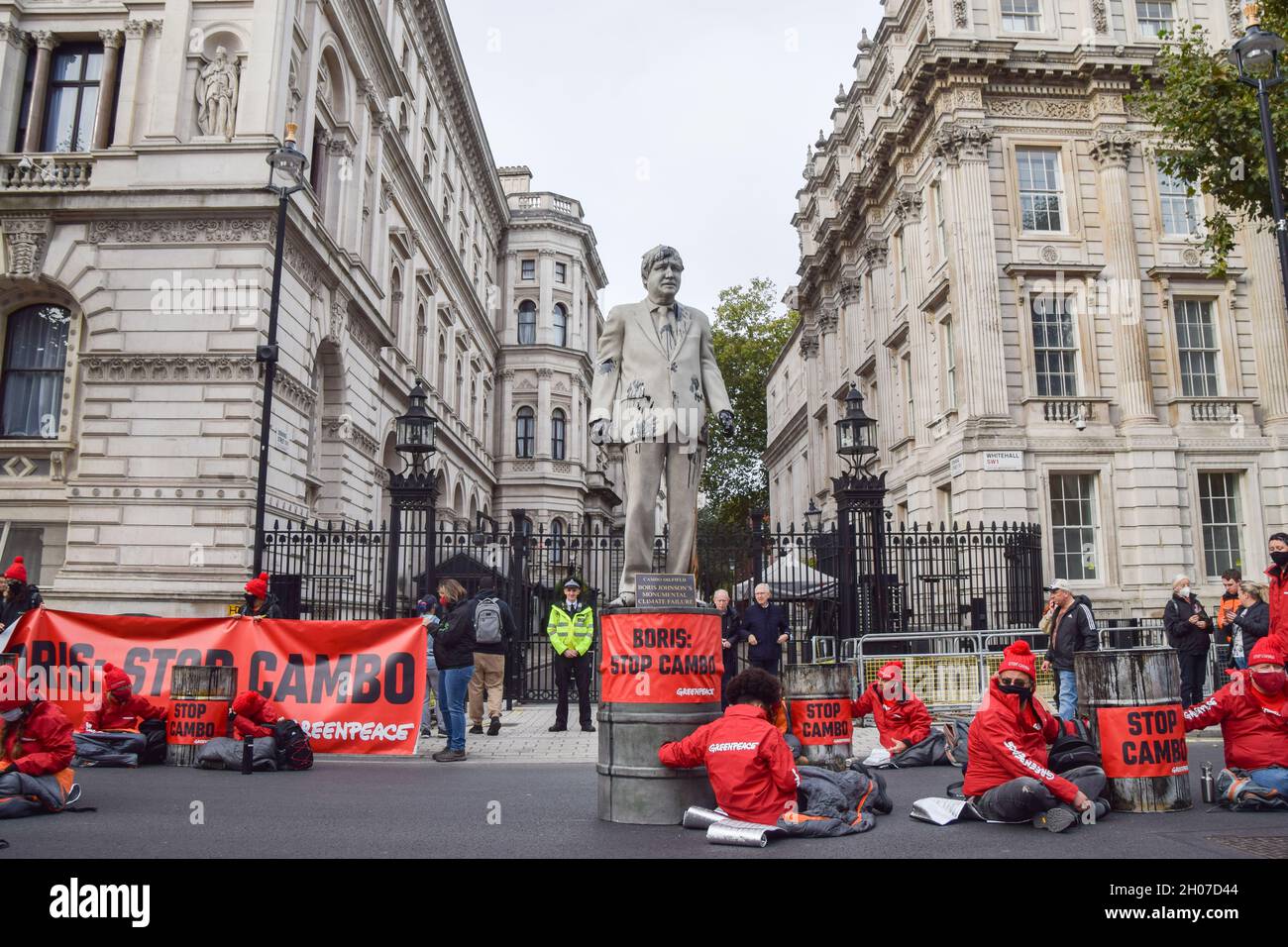 London, UK. 11th Oct, 2021. Activists locked to barrels sit around a statue of Boris Johnson splattered with fake oil, during the Stop Cambo protest.Greenpeace activists locked themselves to barrels and installed a large statue of Boris Johnson smeared in fake oil outside Downing Street, in protest against the Cambo oil field. Credit: SOPA Images Limited/Alamy Live News Stock Photo