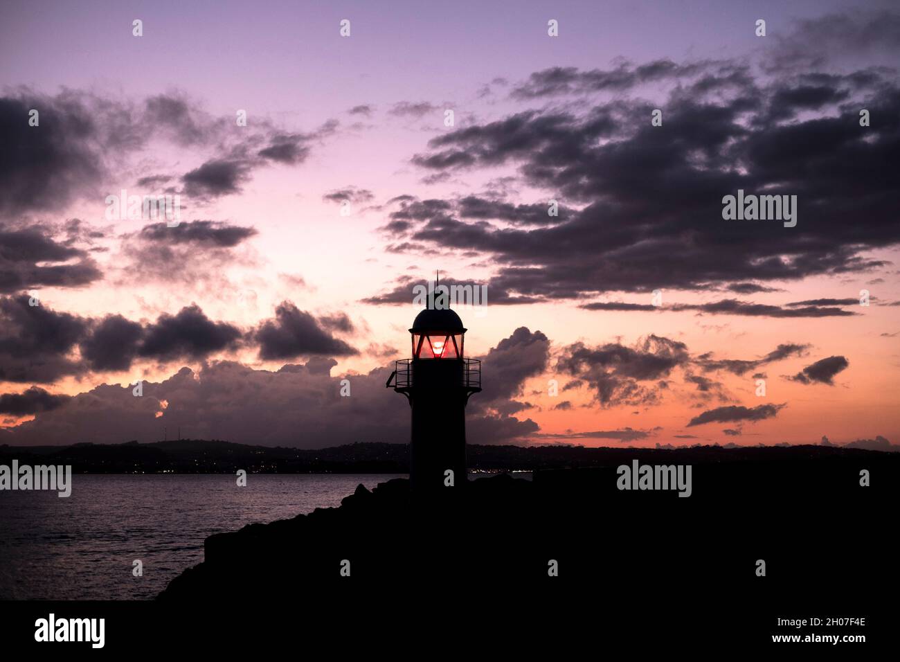 Brixham harbour lighthouse in Brixham, Devon at sun set on a summer evening Stock Photo