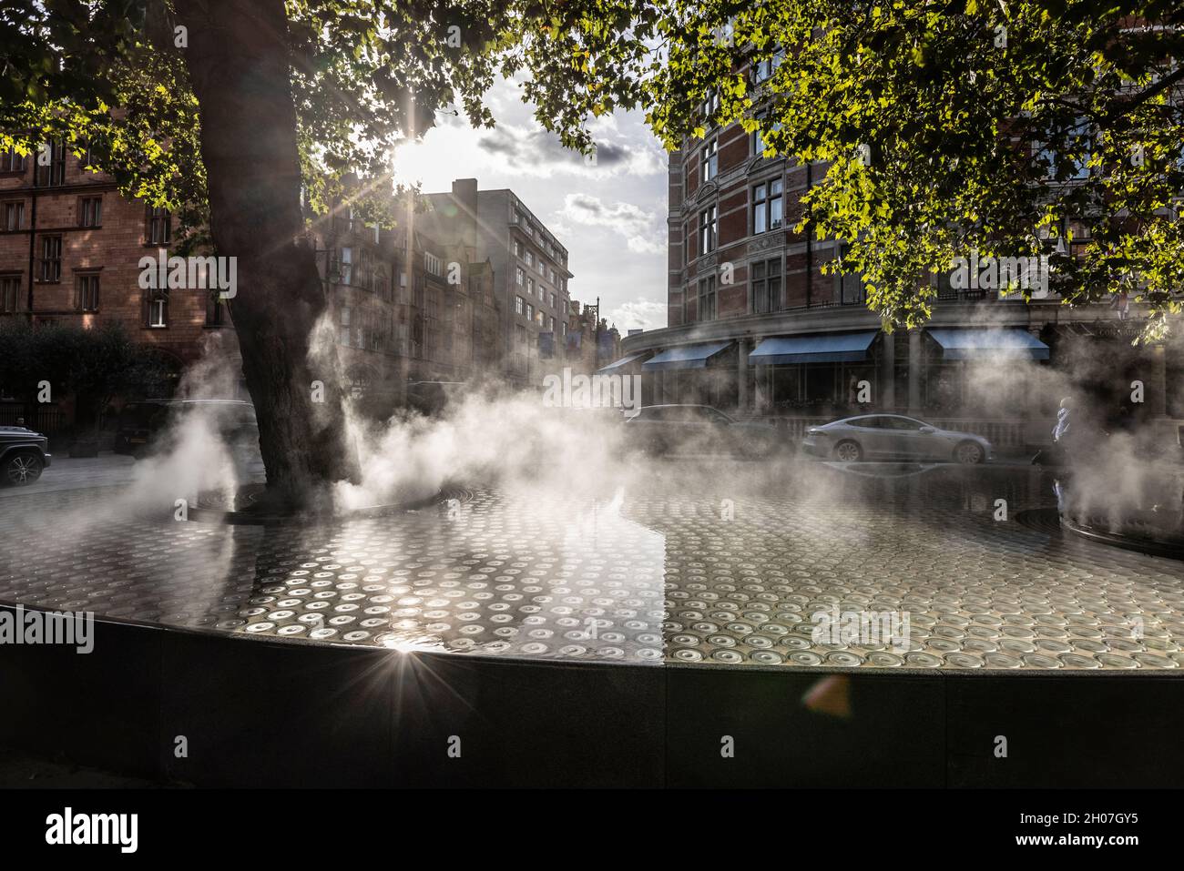 Artificial mist rises in a water feature outside the Connaught Hotel in London's chic Mayfair area, London, England, United Kingdom Stock Photo