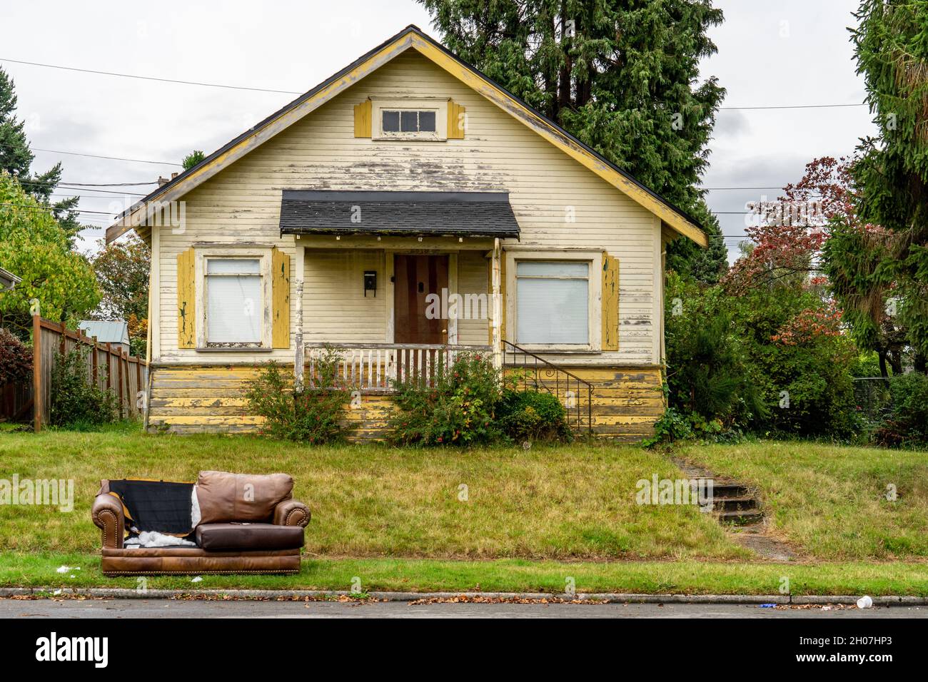 Everett, WA - USA / 10/11/2020: Torn and trashed Couch on front lawn of vacant house Stock Photo