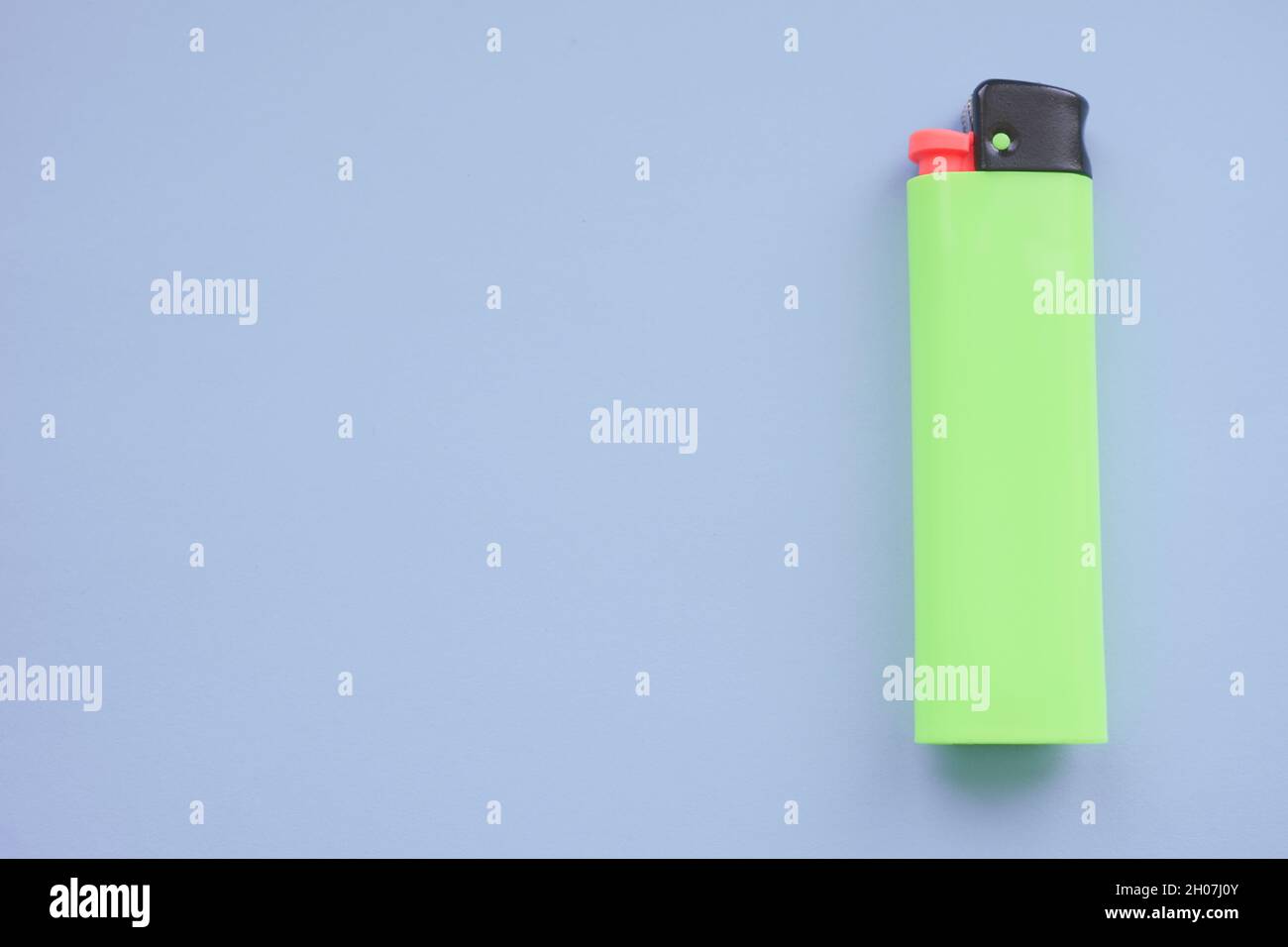 One green lighter on a blue table. Stock Photo