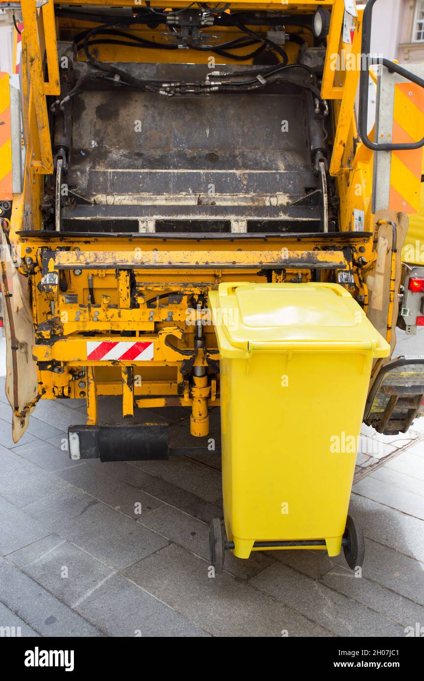 Trash can attached to garbage truck for dump removal in urban street Stock Photo