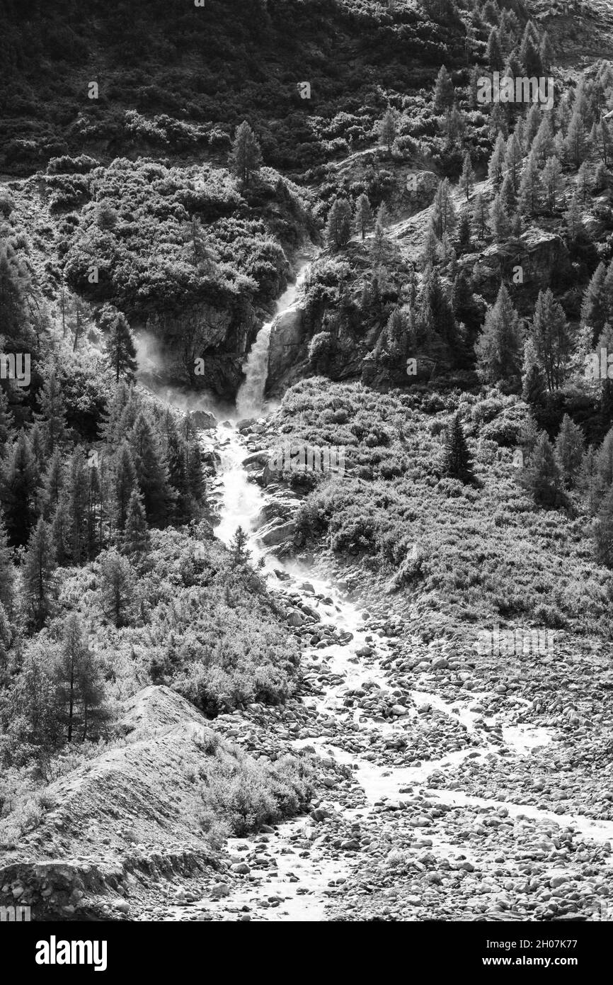 Wild alpine waterfall on Schlatenbach mountain stream. Gschloesstal Valley, Hohe Tauern National Park, East Tyrol, Austrian Alps. Black and white image. Stock Photo