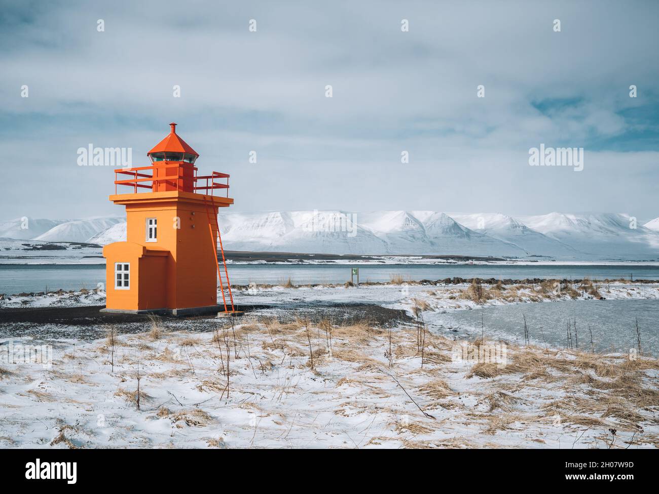 Beautiful view of orange colored lighthouse on the northcoast of Iceland, west Iceland in winter season with volcanic rocks and brown grass on cloudy Stock Photo