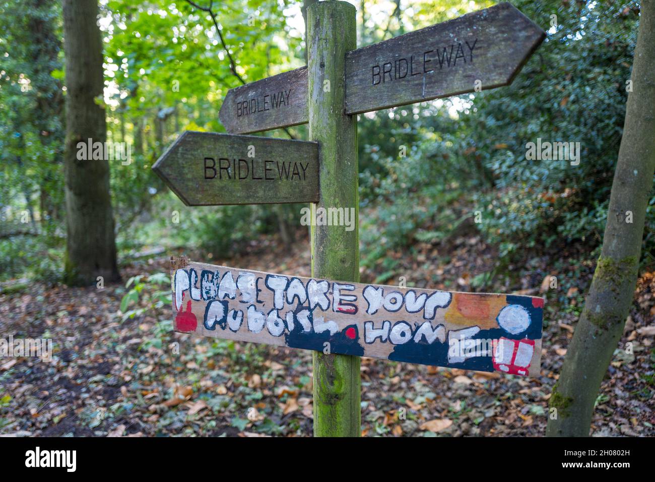 Wooden bridleway sign with Please Take Your Rubbish Home message attached. Stock Photo