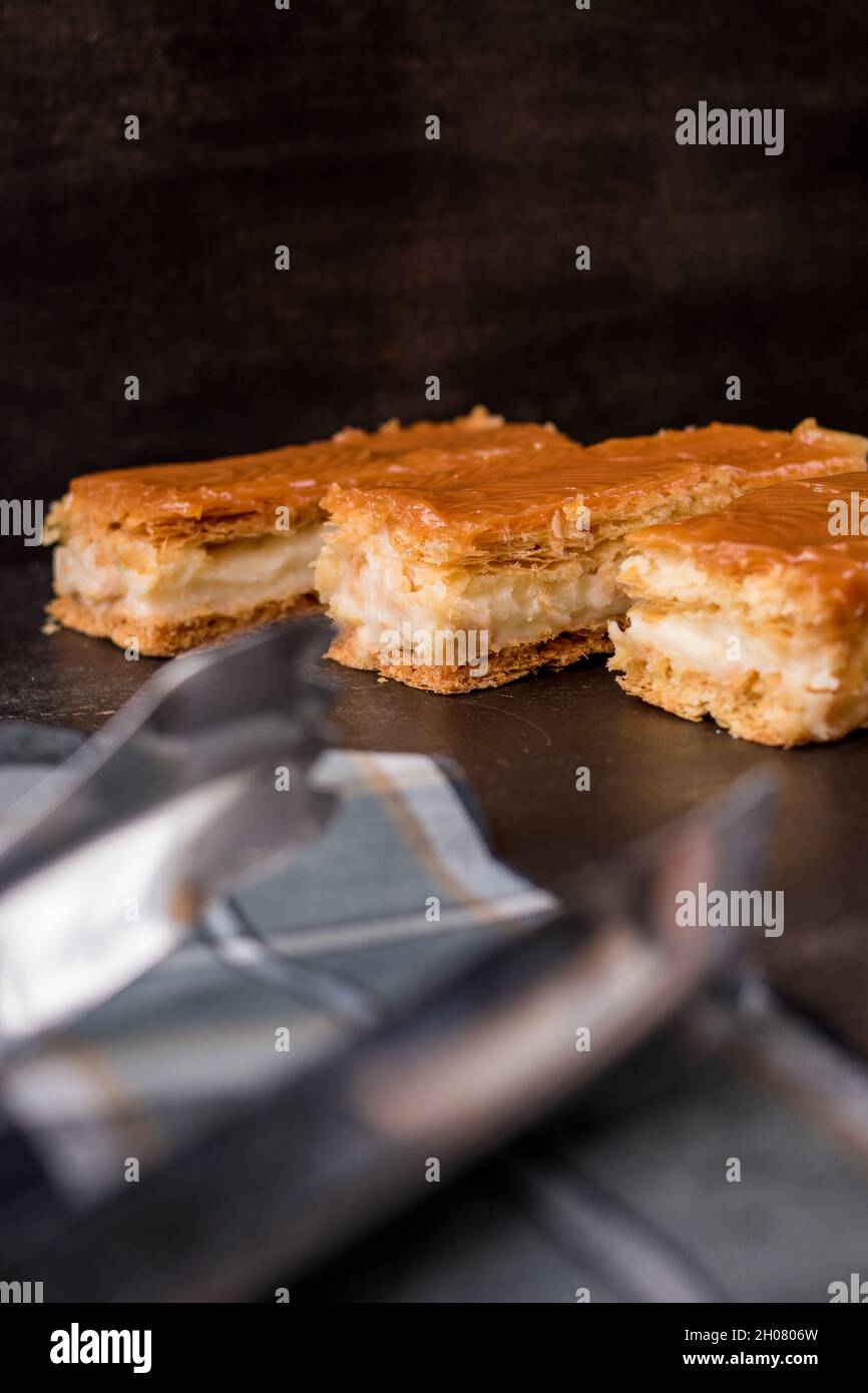 Some caramel sauce snacks with cream and some kitchen's clamps on a black wooden table Stock Photo