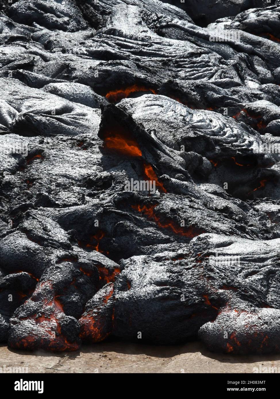 Pahoehoe lava flow at Fagradalsfjall, Iceland. Lava crust is gray and black, molten lava is red and orange. Stock Photo
