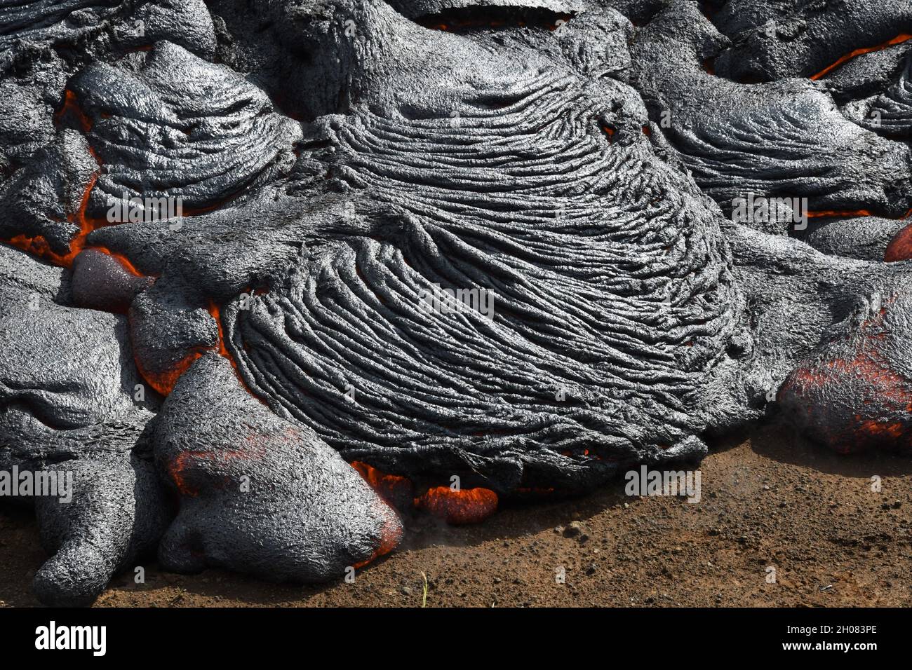 Pahoehoe lava flow at Fagradalsfjall, Iceland. Lava crust is gray and black, molten lava is red and orange. New ropy lava lobe forming. Stock Photo