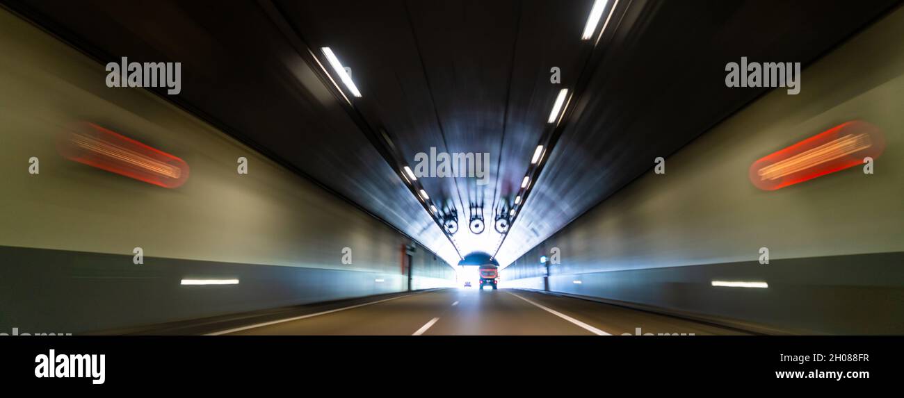 Motion blurred panoramic web banner header photograph of traffic lorry truck and car on a road in a tunnel Stock Photo