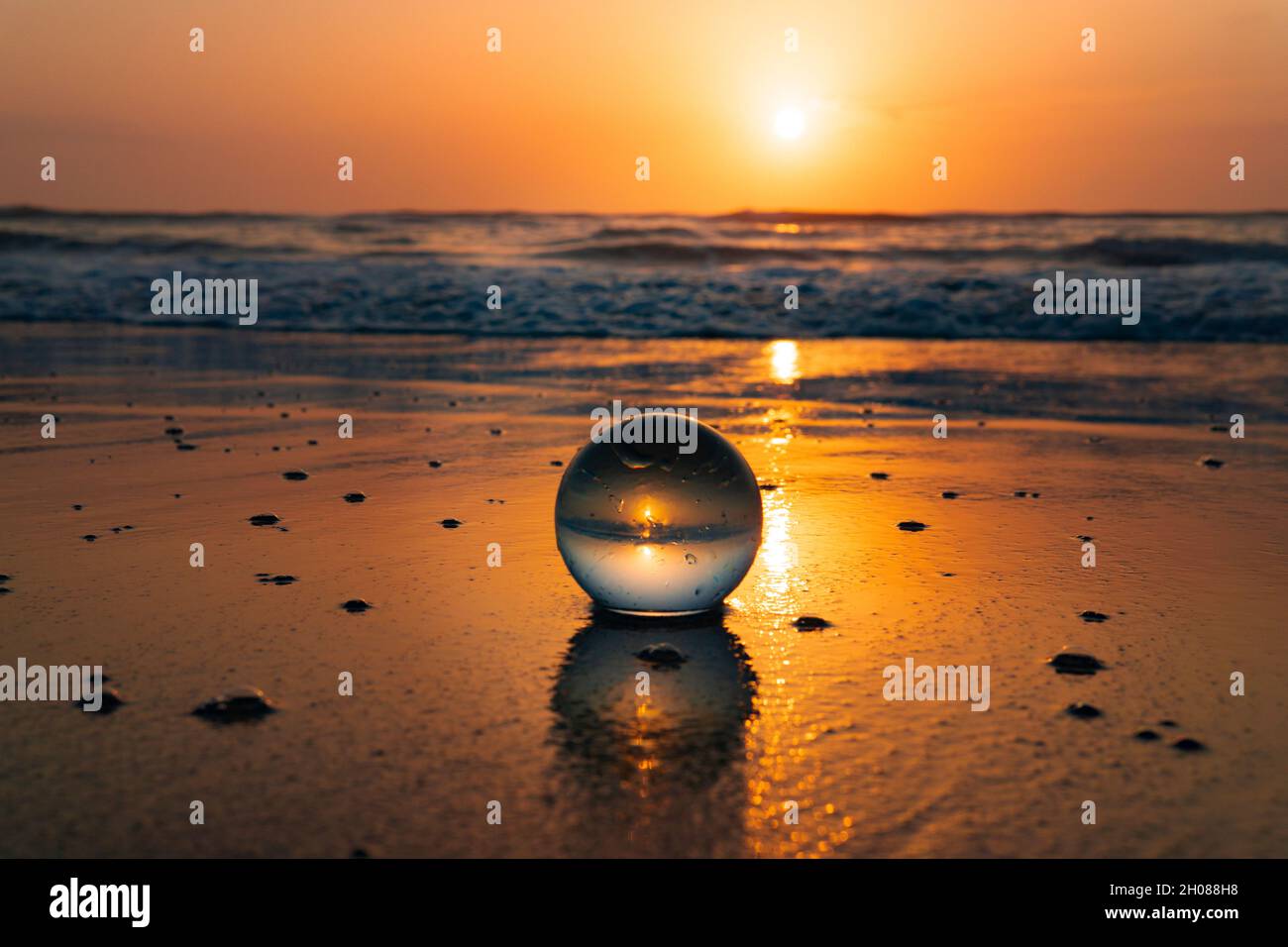 stunning sunrise ocean beach glass ball reflection relaxation Stock Photo