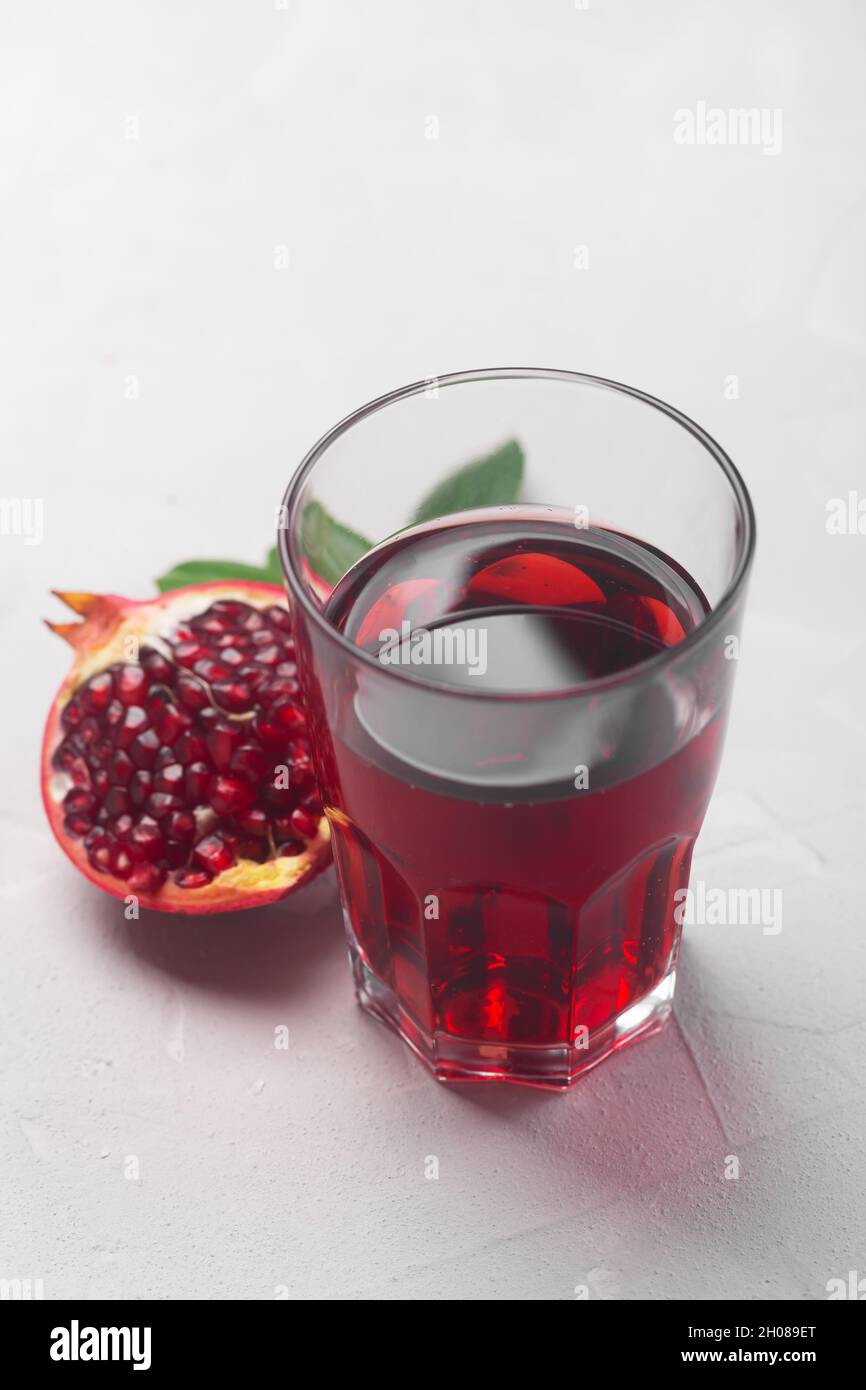 A Jug of pomegranate juice with fresh pomegranate fruits on white