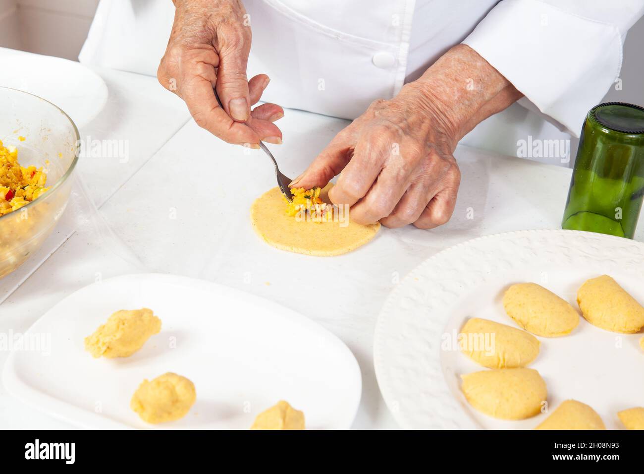 Preparation of the traditional patties from the region of Cauca in Colombia, called empanadas de pipián - Senior woman filling the patties Stock Photo