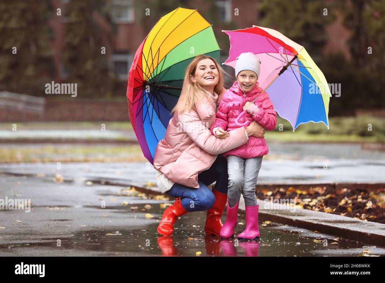 Mother and daughter with umbrellas taking autumn walk in city on rainy ...