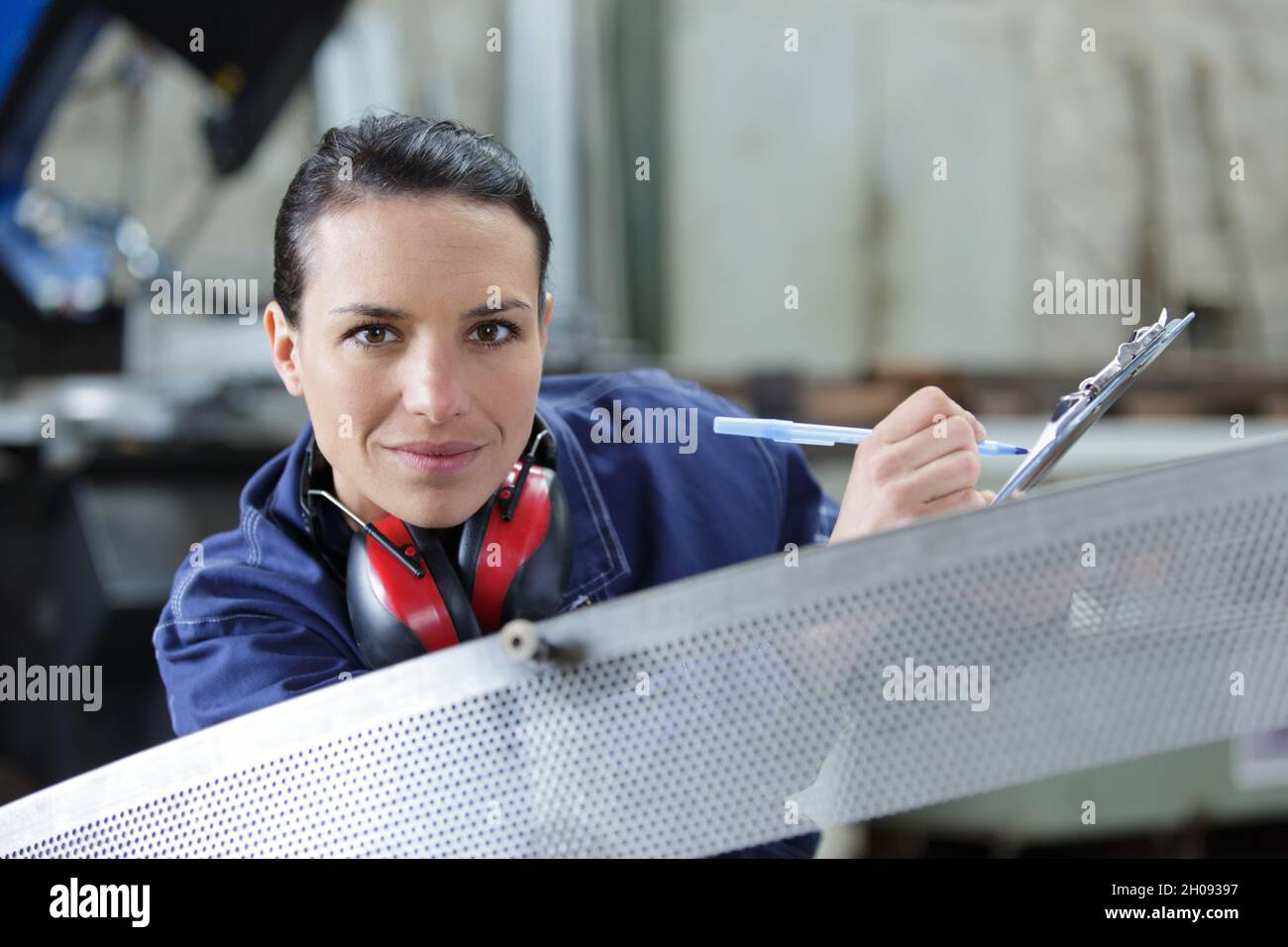 attentive female worker writing on clipboard in olive factory Stock ...