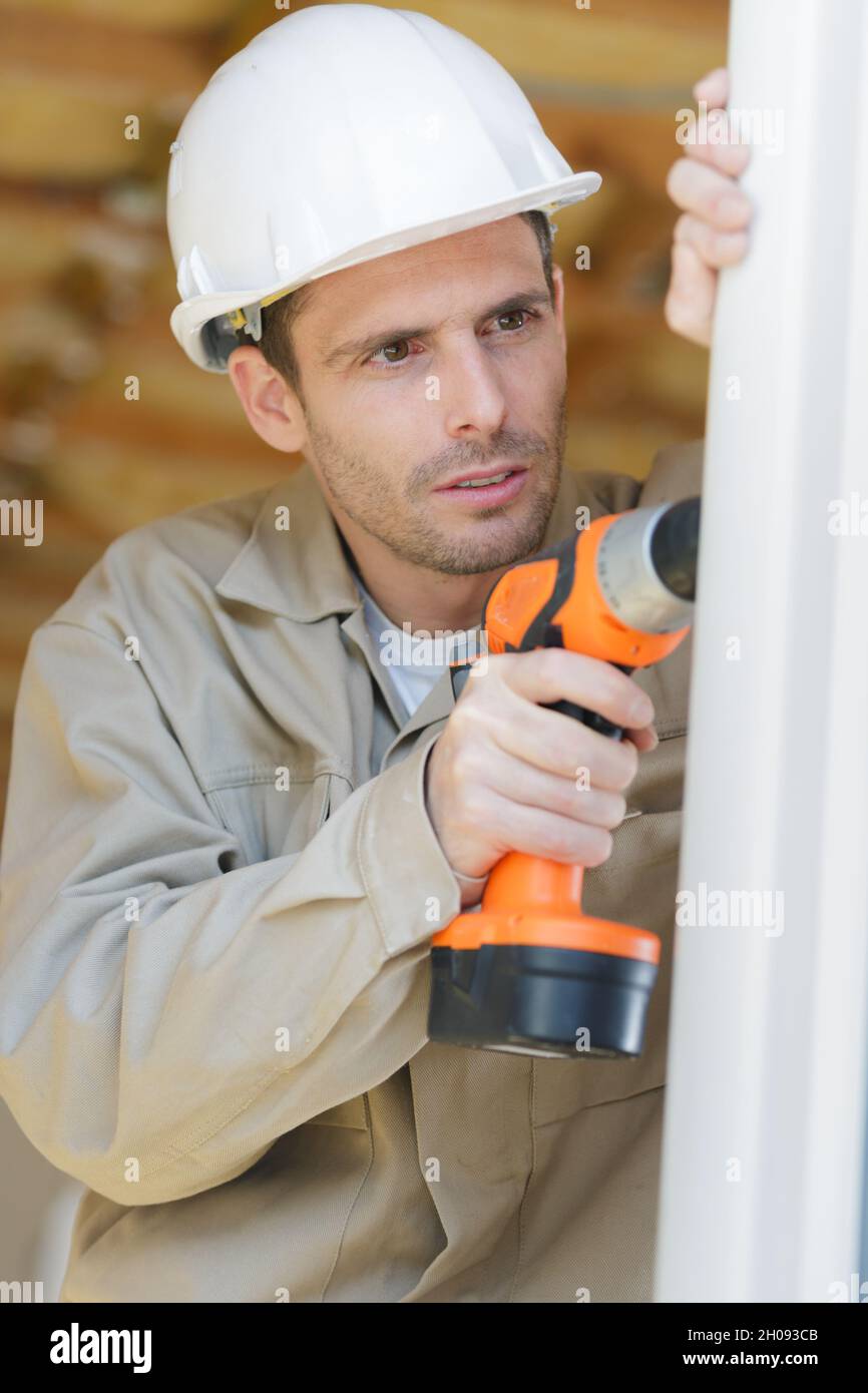man drilling a hole in a window frame Stock Photo Alamy